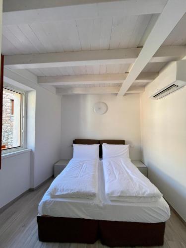 a bedroom with a bed with white sheets at Appartamenti Le Tre Rose in Nago-Torbole