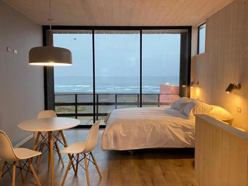 a bedroom with a bed and a table and chairs at Ventana Al Mar in Pichilemu