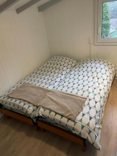 uma pequena cama num pequeno quarto com uma janela em Le Balcon d’Echery em Sainte-Marie-aux-Mines