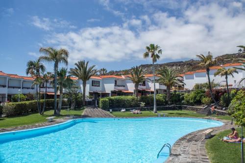 una piscina en el complejo con palmeras y edificios en Apartamento Salinas 2, en Los Cancajos