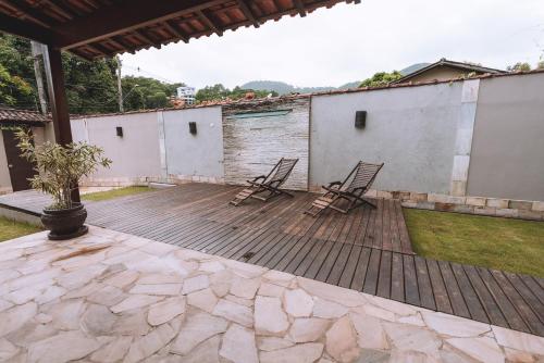 two chairs sitting on a wooden deck in a yard at CASA ALECRIM PISCINA PRIVATIVA COM Dec MOVEL Ideal Crianças in Niterói