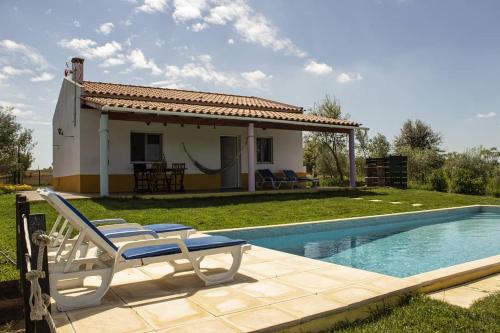 a villa with a swimming pool in front of a house at Monte Quinta Verde in Ferreira do Alentejo