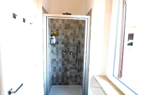 La salle de bains est pourvue d'une douche avec une porte en verre. dans l'établissement Uno sguardo sul mare - appartamento, à Ancône