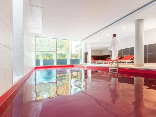 a man standing next to a swimming pool at Novotel Domaine de Maffliers - L'Isle-Adam in Maffliers