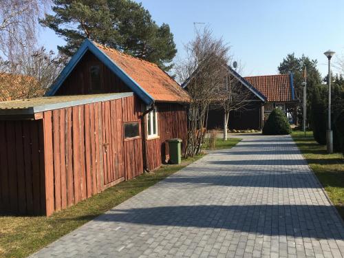 a building with a red roof next to a sidewalk at Waterfront Villa Artvė with sauna - self check-in in Pervalka