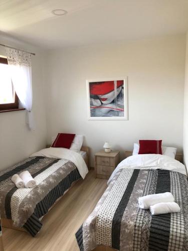 a bedroom with two beds and a picture on the wall at Domek Polny czar in Pogorzelica