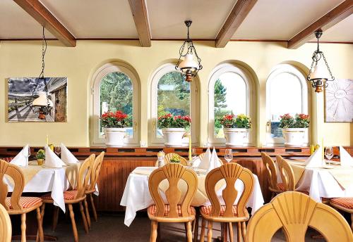 a dining room with tables and chairs and windows at Hotel und Restaurant Petit Robby in Wenningstedt