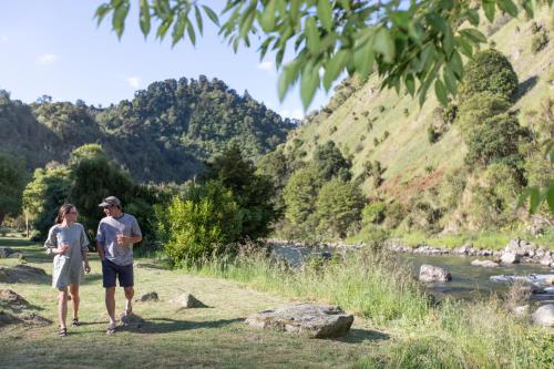 a man and a woman standing next to a river at River Valley Lodge in Taihape