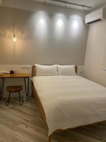 台東市的住宿－曉貳民宿 ，卧室配有白色的床和桌子