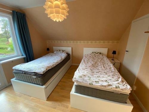 two twin beds in a bedroom with a chandelier at Villa Movägen • Fast Free Wifi • AC • 10 min from lake in Mörlunda