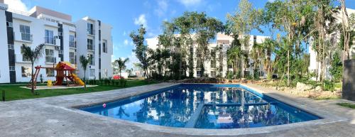 a swimming pool with a playground in front of a building at Departamento Vacacional 2 habitaciones vista a la alberca by EITA in Cancún