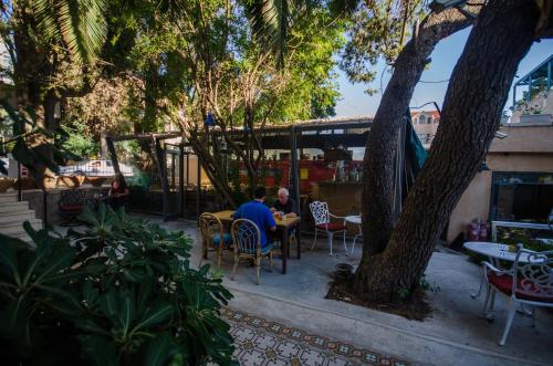 a man sitting at a table under a tree at Jerusalem Garden Home in Jerusalem