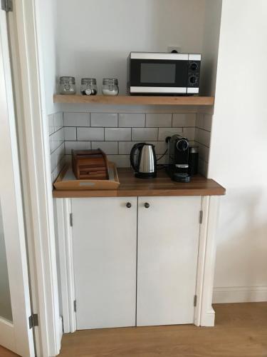 a kitchen with a counter with a microwave on a shelf at Stunning pied-a-terre moments from the water. in Netley