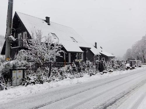 a house is covered in snow on a street at Agroturystyka,, Ranczo Kruszynki" in Stronie Śląskie