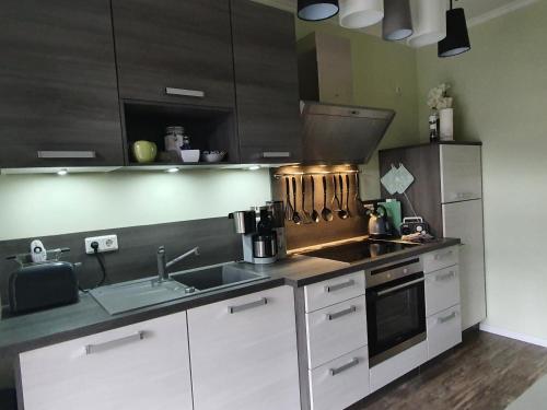 a kitchen with white cabinets and a sink and a stove at Ferienwohnung ODIN, FREYA & THOR in Thale