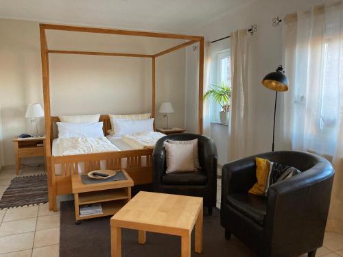 a living room with a bed and two chairs at Landhaus-Apartments in Wattenheim