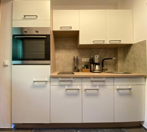 a kitchen with white cabinets and a stove top oven at Appartement Gabriela ACHTUNG nur Feriengäste willkommen,es ist keine Arbeiterunterkunft in Obernzell