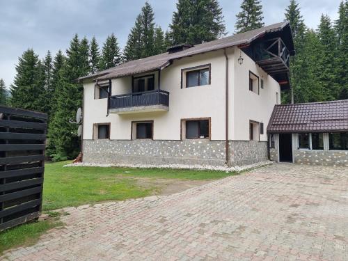 a large white house with a stone wall at Cabana Laptici - statiunea Pestera-Padina, Bucegi in Sinaia