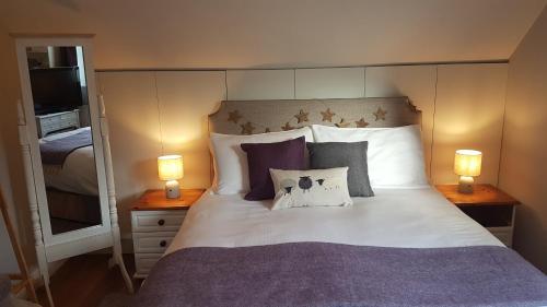 ein Schlafzimmer mit einem großen Bett mit Kissen und zwei Lampen in der Unterkunft Post Office Row Apartment and garden in Crickhowell