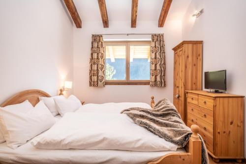 ein Schlafzimmer mit einem Bett und einem TV auf einer Kommode in der Unterkunft Chalet-Appartement mit Penthouse Flair in Bad Hofgastein