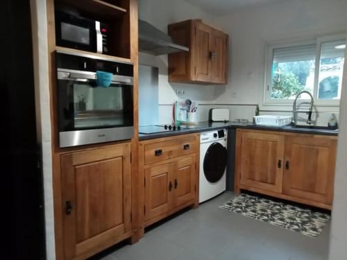 une cuisine avec des armoires en bois et une laveuse et une sécheuse dans l'établissement La Maison du soleil & du sourire, à Nîmes