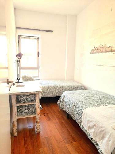 a bedroom with two beds and a table with a lamp at TOLETUM low cost LOFTS diáfanos o 2dormitorios PARKING Municipal Gratis al aire libre a 100m in Toledo