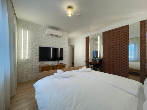 a bedroom with a large white bed and a flat screen tv at ConnectIN Apartments in Pale