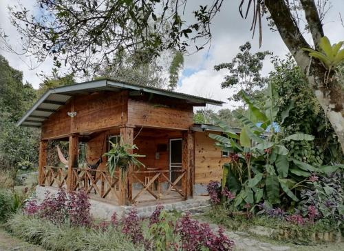 a wooden cabin with a porch in a garden at Lita's Place in Cordillera Arriba