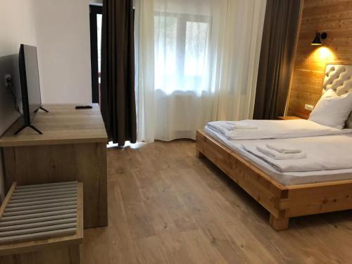 1 dormitorio con 1 cama y TV en Pensiunea Armonia Albac en Albac