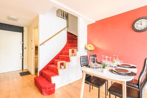 une salle à manger avec un mur rouge et un escalier dans l'établissement Appartement spacieux vue Cathédrale, à Reims