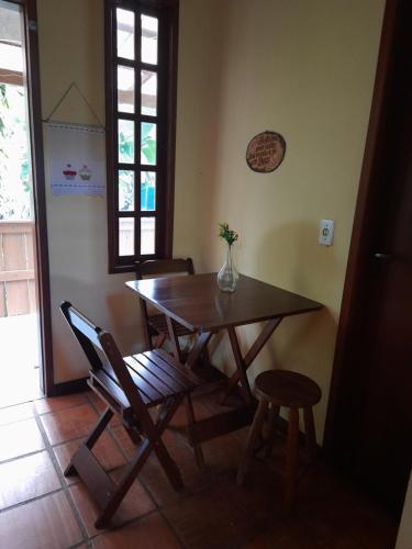 a dining room table and chairs with a vase on it at Chalé Lumiar M&C in Lumiar