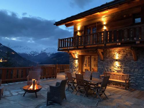 a patio with a table and chairs and a building at Chalet Ruitor, chalet 500 m2 luxueux de caractère in Sainte-Foy-Tarentaise