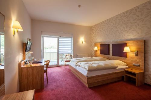 a hotel room with a large bed and a desk at Hotel Pfaffenhofen in Schwabenheim