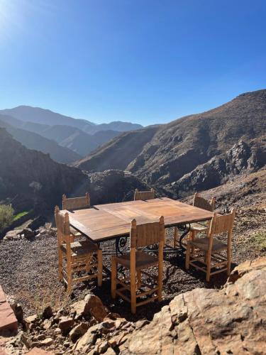 a wooden table and chairs on top of a mountain at Issouganes N Toubkal Maison d hôtes in Oussertek