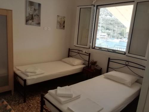 two beds in a room with a window at Aristoula House in Sivota