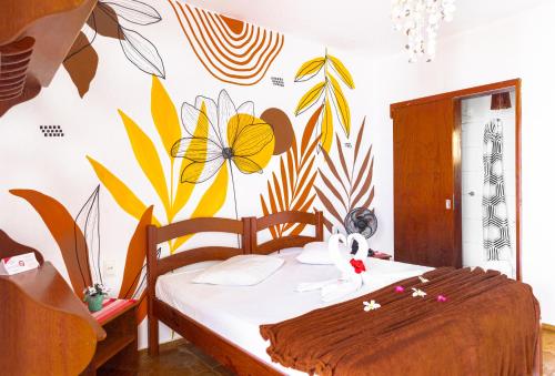 a bedroom with a bed with a flower mural on the wall at Cumbuco Kite in Paradise e Hospedaria in Cumbuco