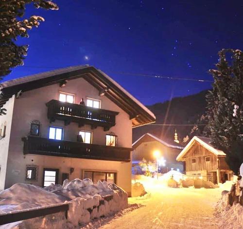 a building with a balcony in the snow at night at Gasthof Barlida in Lainach