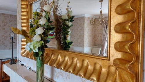 a mirror on a wall with a vase with flowers at Kilronan Holiday Homes in Kilronan