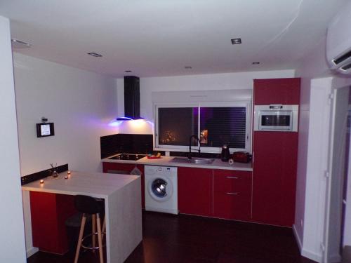 una cucina con armadi rossi e una lavatrice di Loveroom 54 a Jarville-la-Malgrange