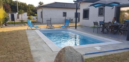 - une piscine avec des chaises, une table et un parasol dans l'établissement Villa Cosy avec piscine privative, à Ghisonaccia