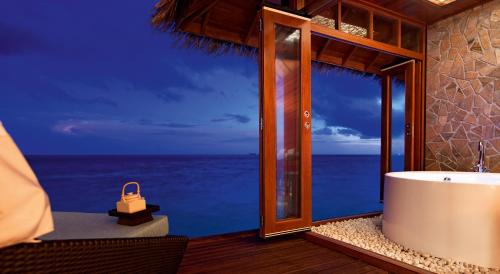 a bathroom with a tub and a view of the ocean at Constance Halaveli in Hangnaameedhoo