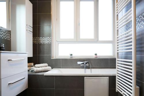 ein Bad mit einem Waschbecken und einem Fenster in der Unterkunft Appart T3 Spacieux & Cosy Face à la gare in Lens