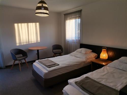 1 dormitorio con 2 camas, mesa y sillas en Jonathan Bed&Pizza, en Komárom