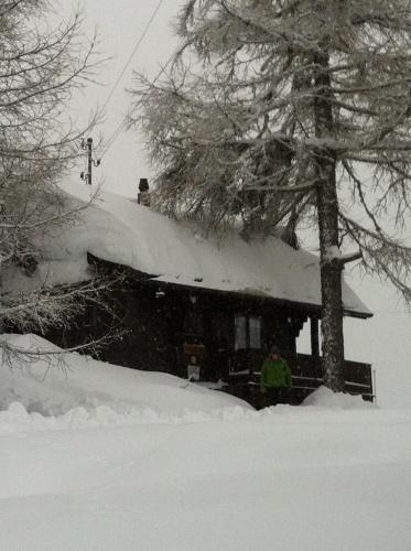 a man standing in front of a house covered in snow at Chalet Balfrin Alpweg 9, 3987 Riederalp in Riederalp