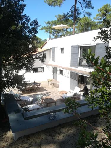 una casa bianca con terrazza e sedie di Villa Paradis Pyla sur Mer a La Teste-de-Buch