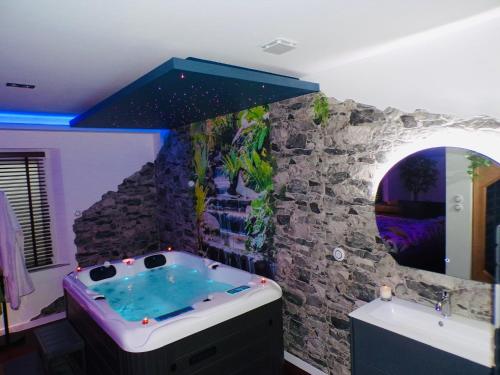 een badkamer met een bad en een stenen muur bij Loveroom 54 in Jarville-la-Malgrange