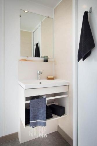 une salle de bain blanche avec un lavabo et un miroir dans l'établissement Mobil home A 04, à Le Portel