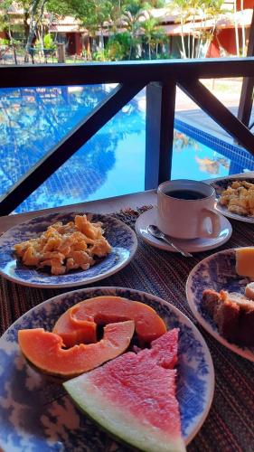 - une table avec des assiettes de fruits et une tasse de café dans l'établissement Pousada Meraki, à La Serra do Cipo