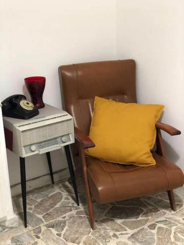 a brown chair with a yellow pillow next to a table at Tabula House - 4 ELEMENTS in Catania
