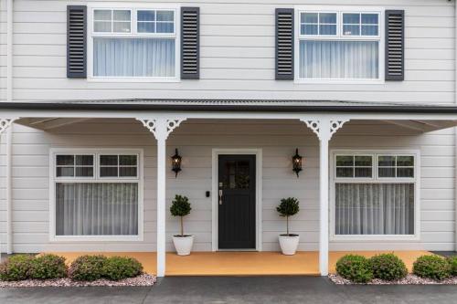 a white house with a black door and two potted plants at Foxmount Estate - Ilo in Mount Gambier